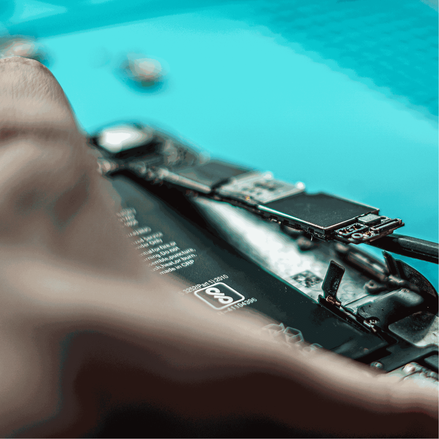 Close-up of hand holding a soldering iron working on a blue circuit board